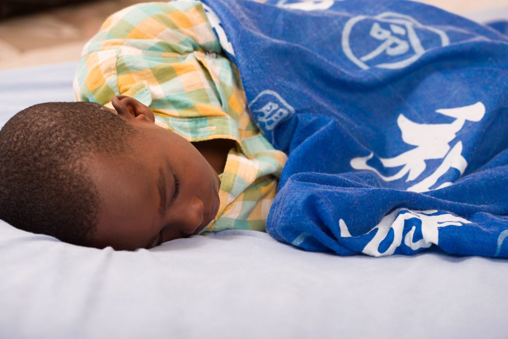 A young boy sound asleep with a healthy sleep pattern.