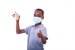 A boy ready for back to school with a mask on and a sanitizer